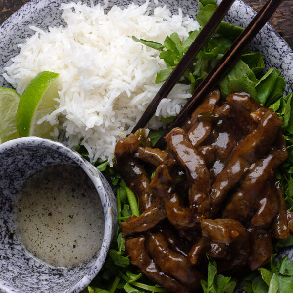 beef and watercress stir fry on platter with rice and dipping sauce