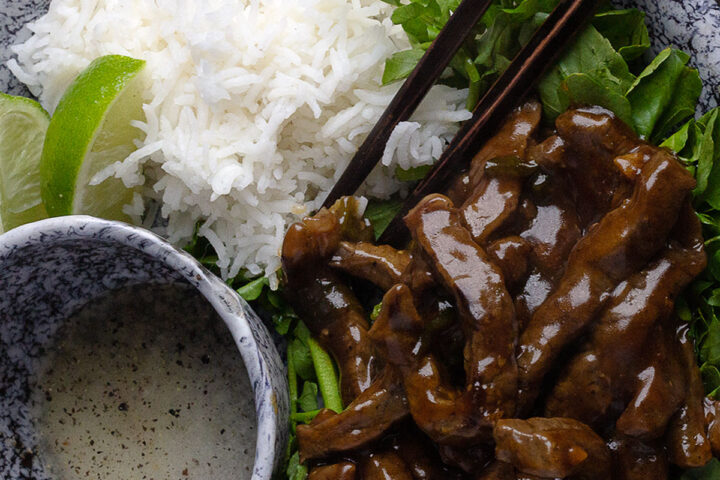 beef and watercress stir fry on platter with rice and dipping sauce