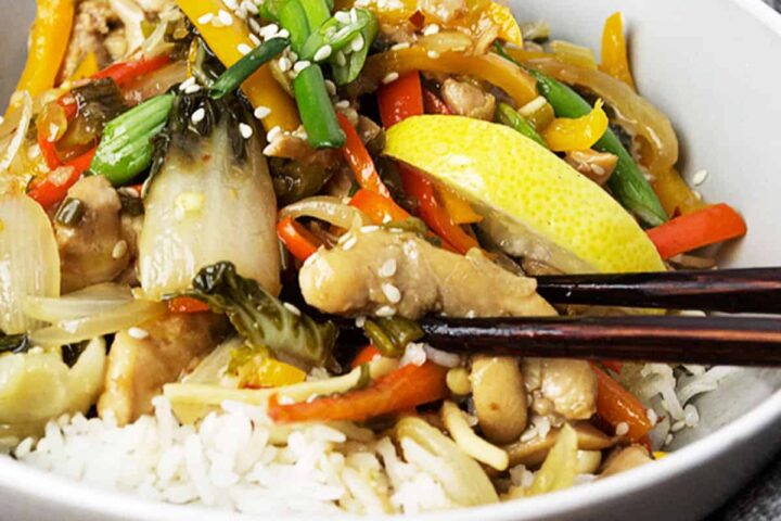 lemon chicken stir fry in bowl with rice and chopsticks