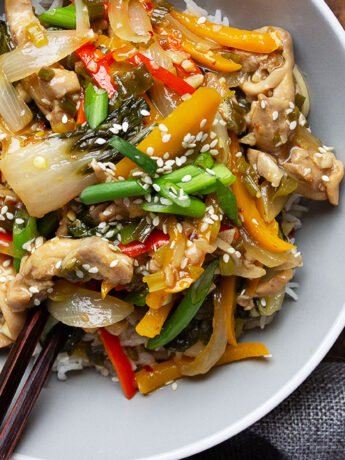 lemon chicken stir fry in bowl with rice and chopsticks