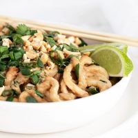 spicy peanut noodles in white bowl with chopsticks