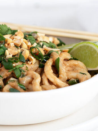 spicy peanut udon noodles in bowl with chopsticks