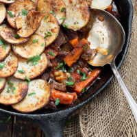 sliced potato topped beef hot pot in cast iron skillet