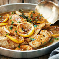 charred lemon chicken in pan with spoon