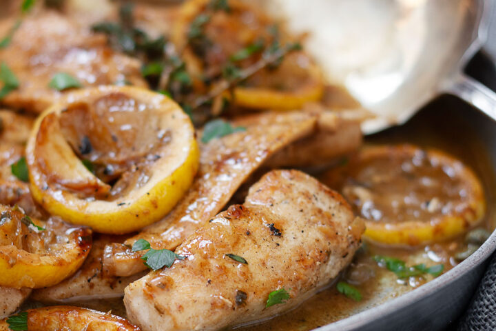 charred lemon chicken in serving dish with spoon