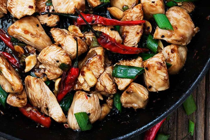 kung pao chicken in cast iron skillet with peppers