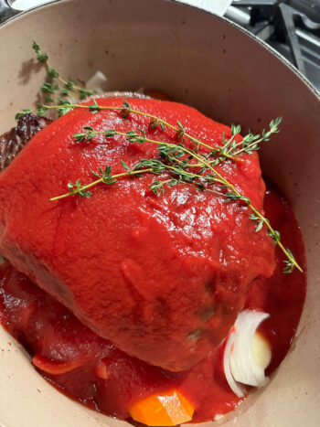 tomato sauce poured over beef roast in pot