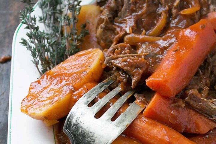 tangy tomato pot roast on plate with carrots and potatoes