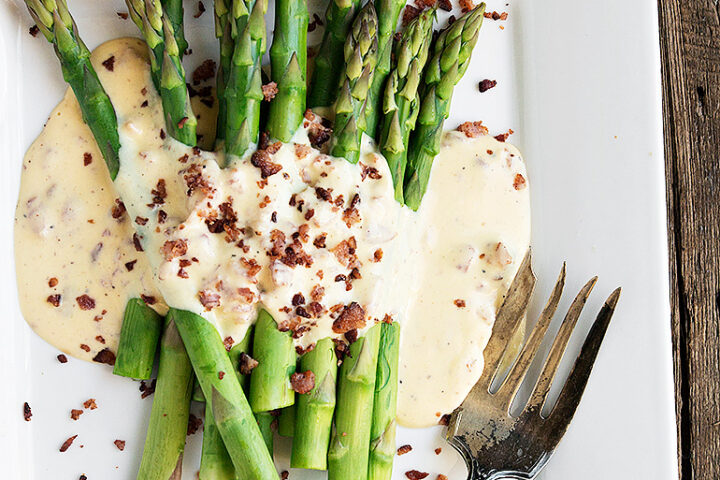 asparagus on a white plate with carbonara sauce and fork