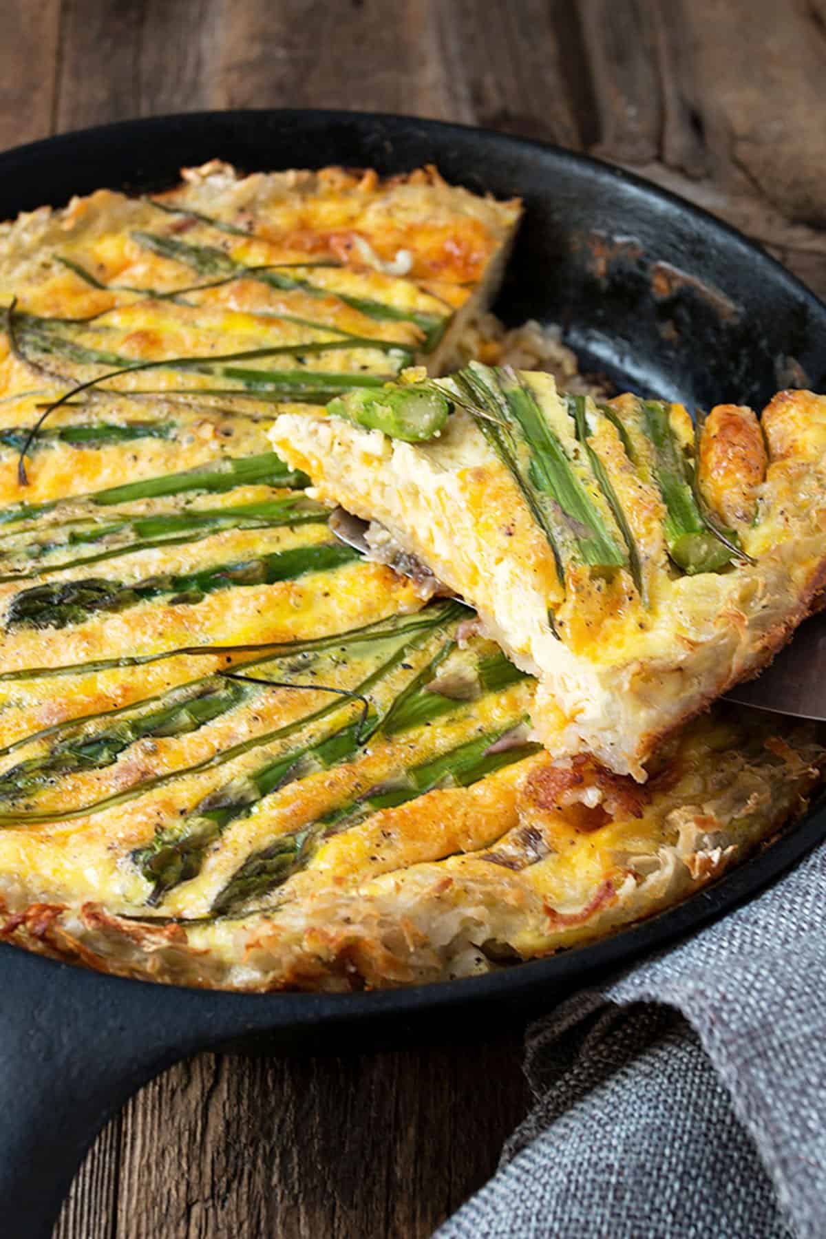 Asparagus quiche with a hash brown crust in cast iron skillet.