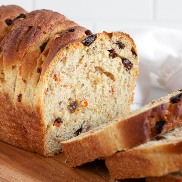 Carrot raisin yeast bread sliced on a cutting board.