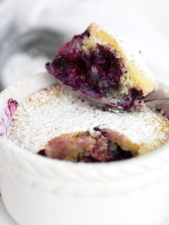 Blueberry pudding cake in ramekins with spoon.