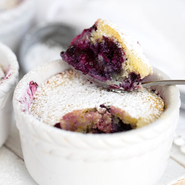 Blueberry pudding cake in ramekins with spoon.