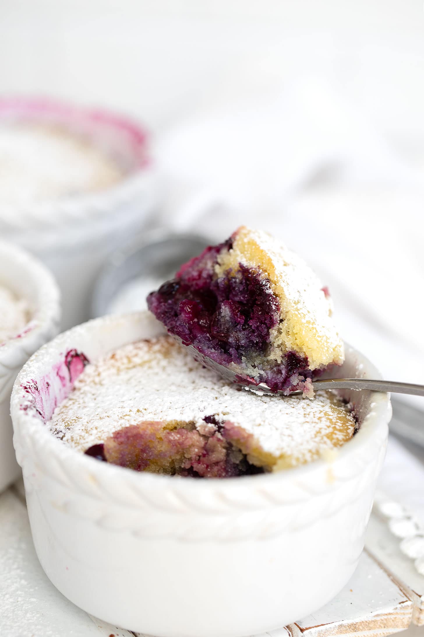 Blueberry pudding cake in ramekins with spoon.