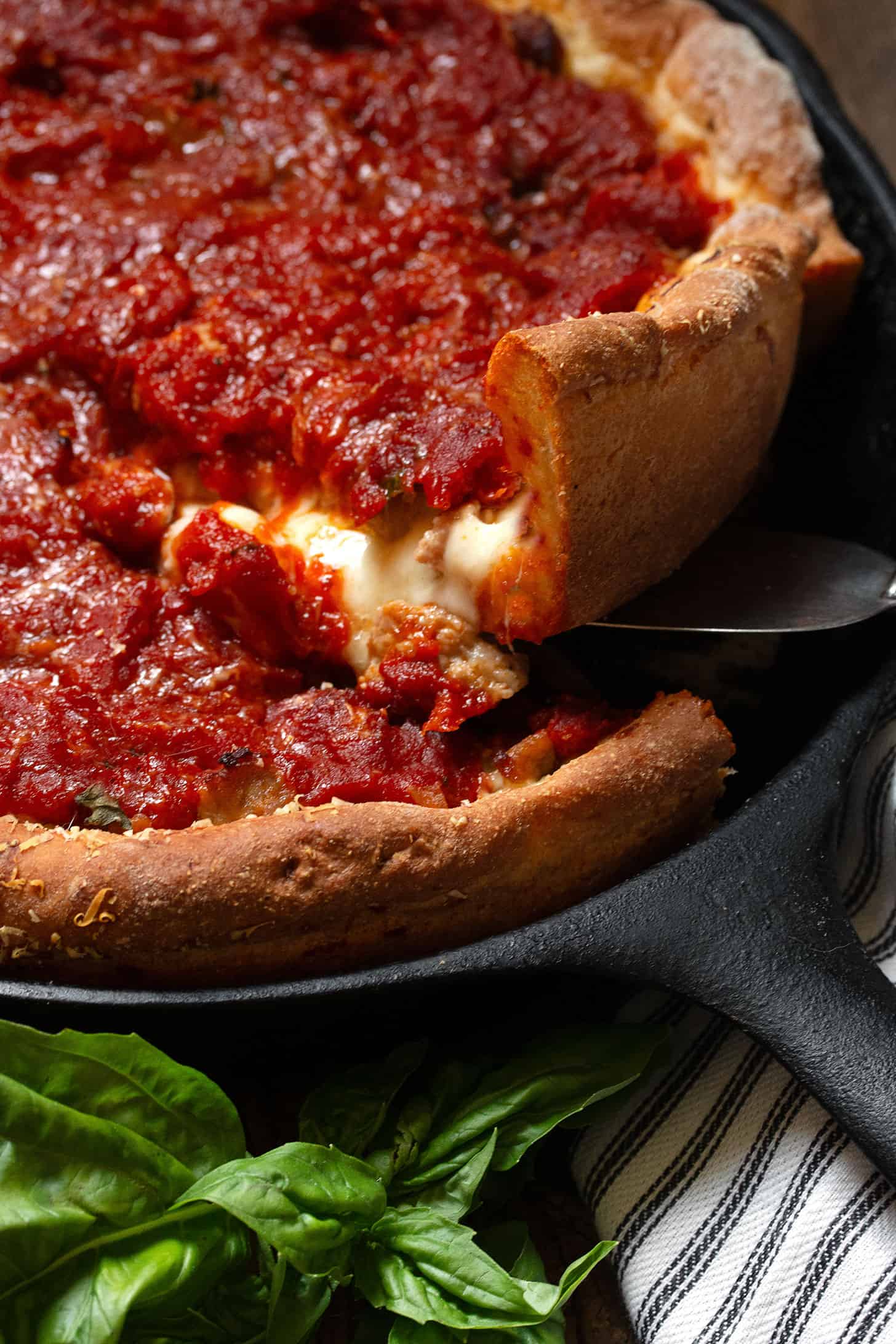 Lifting a slice of Chicago style deep dish pizza in a cast iron skillet.