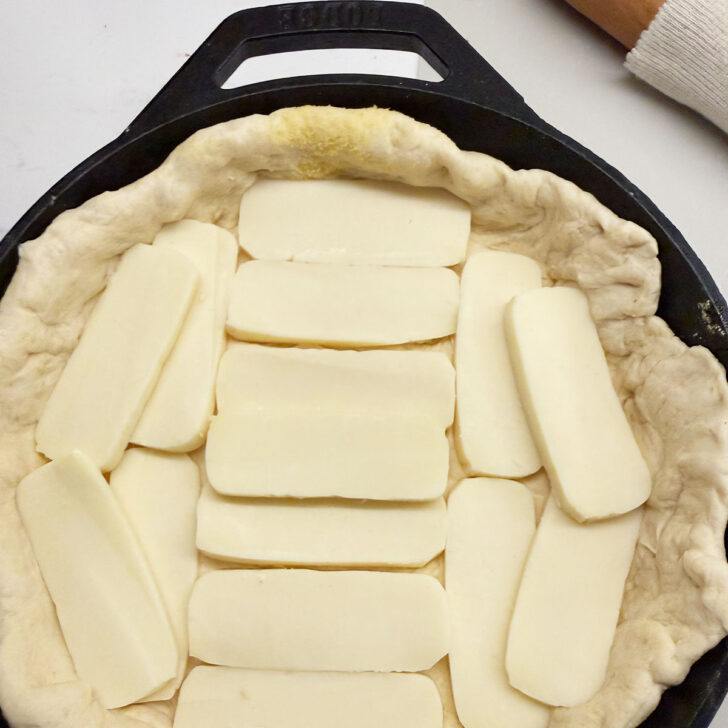 Sliced mozzarella lining placed onto the pizza dough.