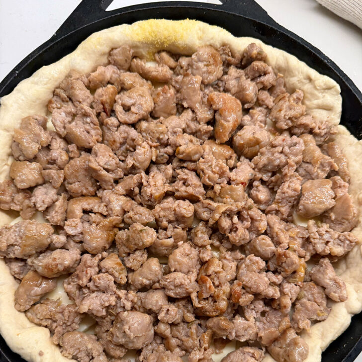 Cooked sausage crumbles added to the deep dish pizza.