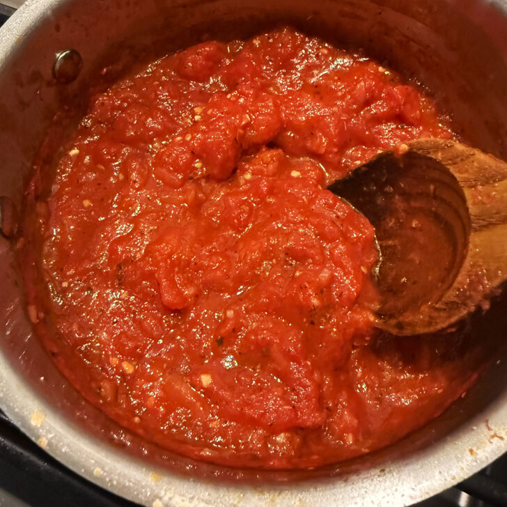 Pizza sauce simmering in a saucepan.