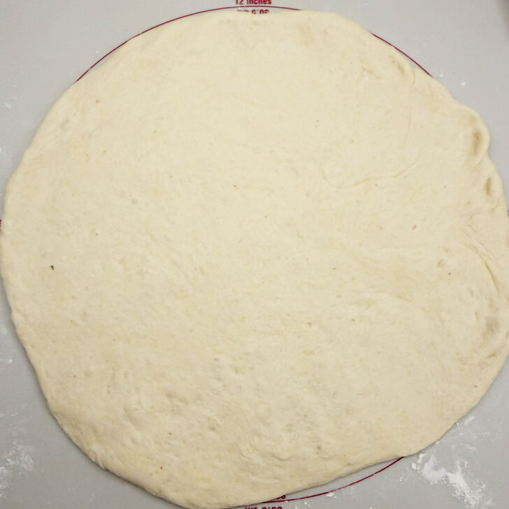 Pizza dough rolled out into a 12-inch circle.