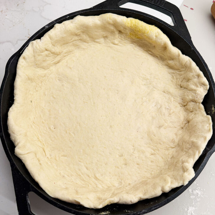 Pizza dough pressed into the cast iron skillet.