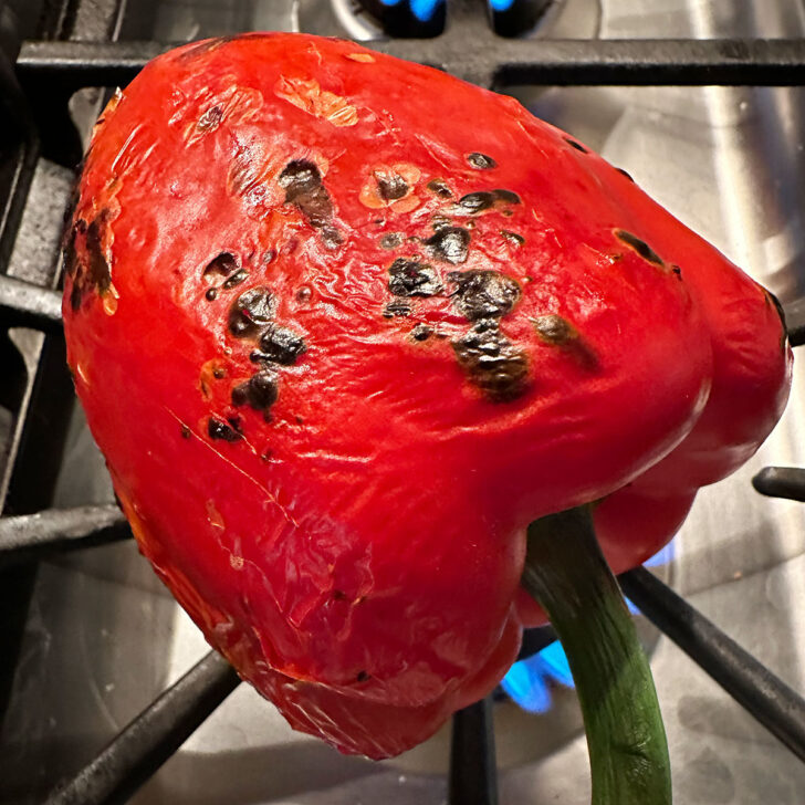 Roasting a red pepper on a gas stove.