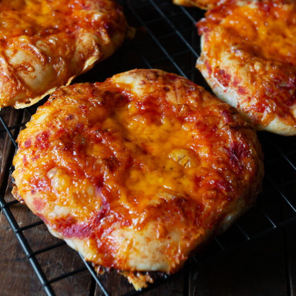 Pizza buns cooling on a wire rack.