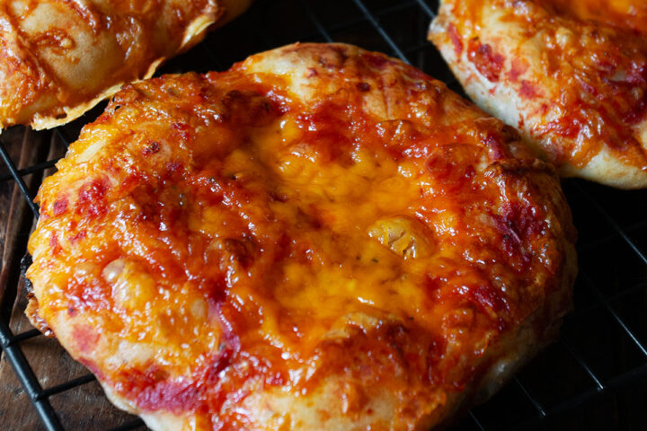 Pizza buns cooling on a wire rack.