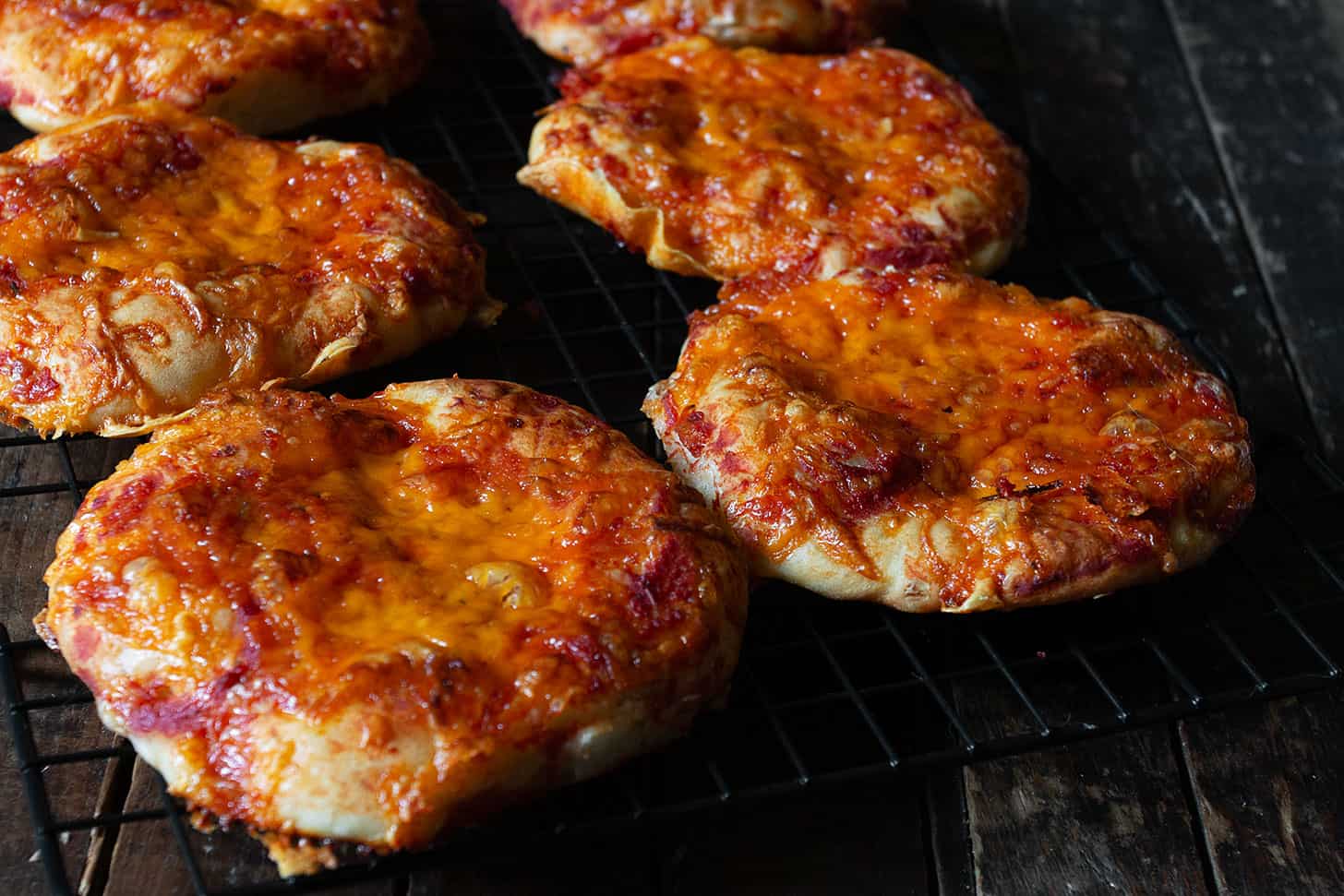 Pizza buns cooling on a wire rack.