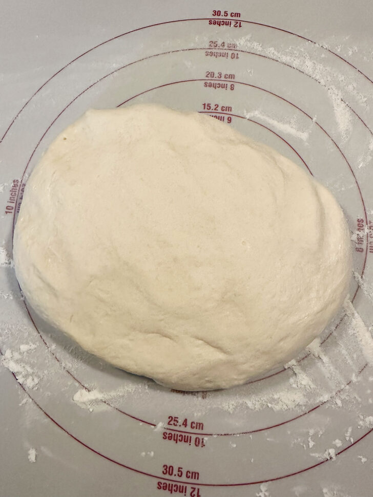 Pizza buns dough removed to a floured work surface.