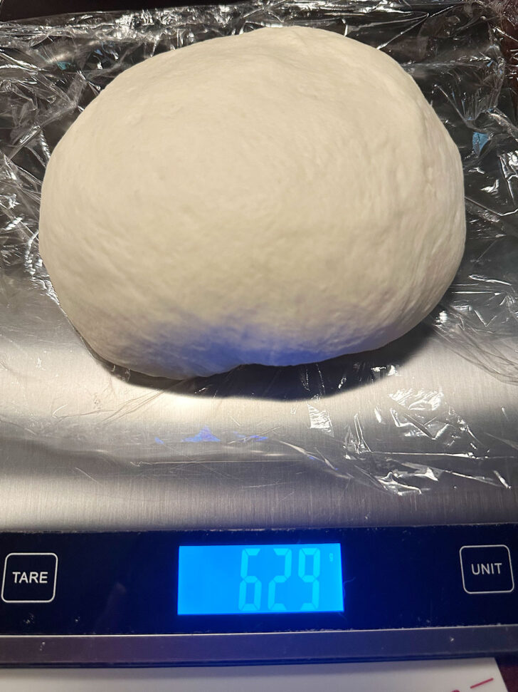 Weighing out the pizza buns dough on a scale.