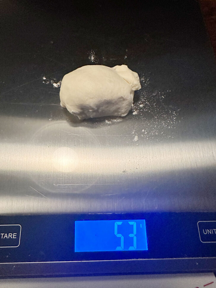 Weighing out the individual pizza buns on a scale.