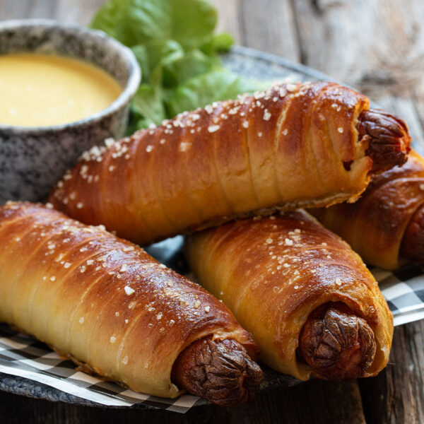 pretzel wrapped hot dogs in platter with mustard sauce