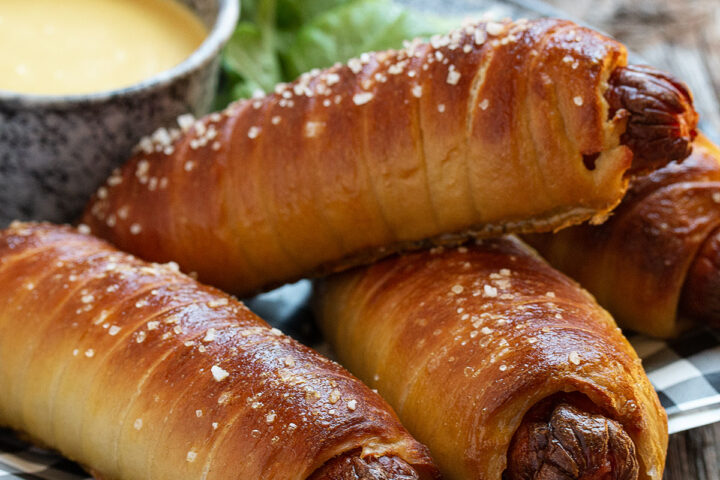 pretzel wrapped hot dogs in platter with mustard sauce