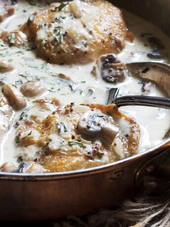 chicken with creamy mushroom tarragon sauce in skillet with spoon