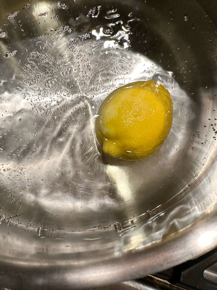 Lemon in boiling water in pot.