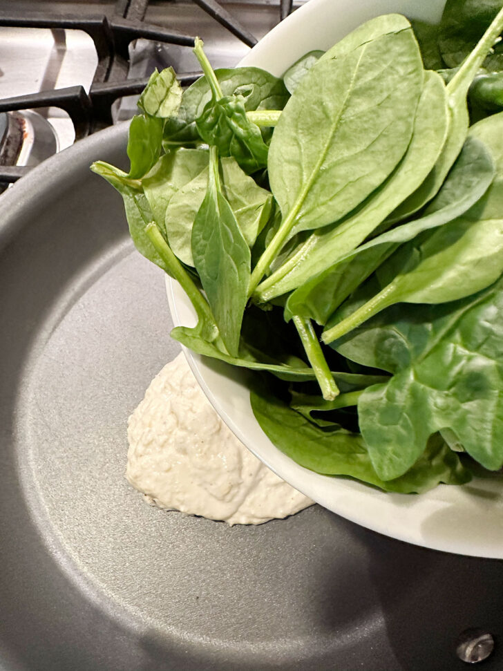 Adding spinach to skillet.