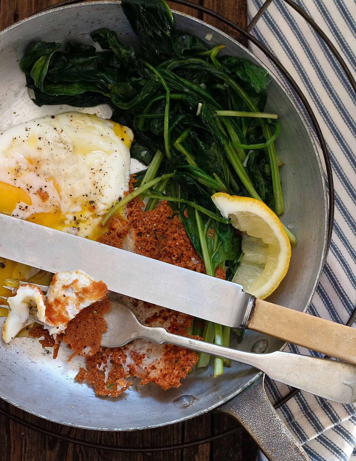 crispy Parmesan eggs in skillet with spinach