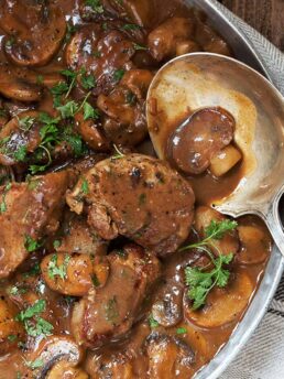 pork medallions with mushrooms and marsala sauce in pan