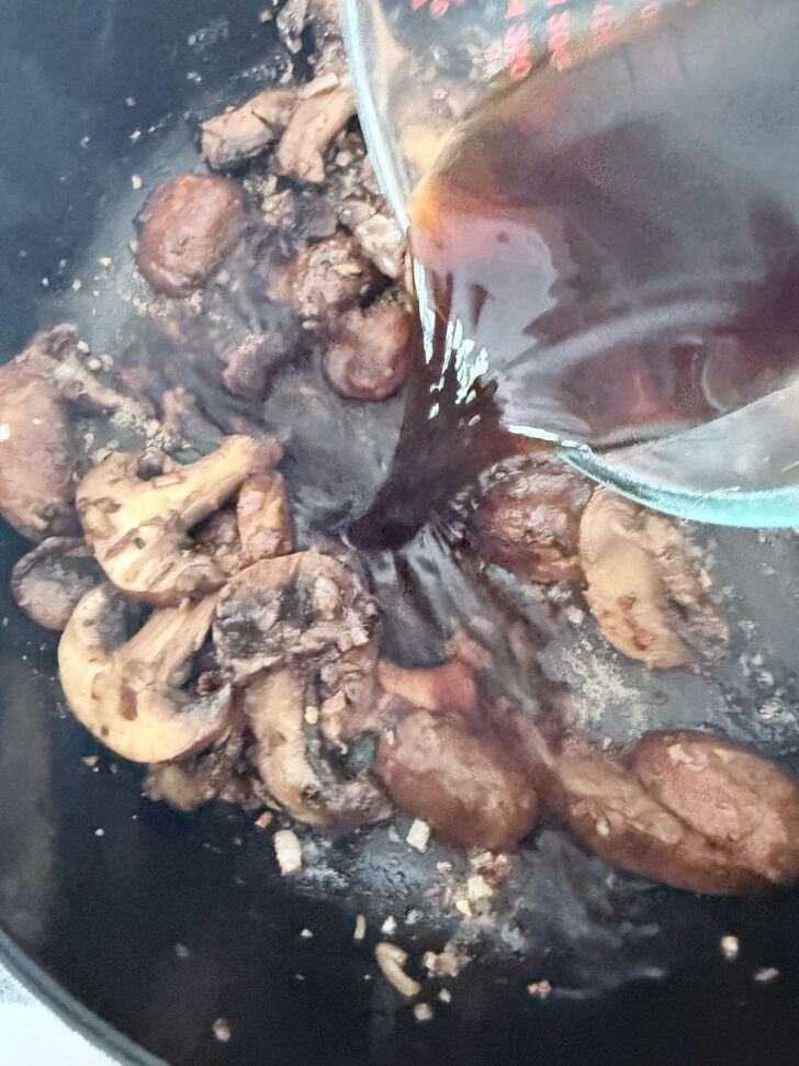 Adding Marsala wine to the skillet with the mushrooms.