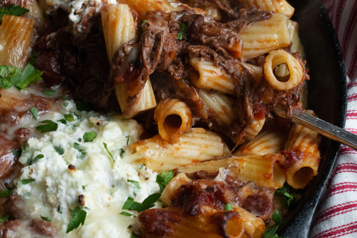 baked pasta with brisket ragu and ricotta in cast iron skillet