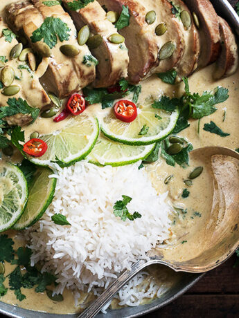 Thai green curry pork tenderloin on platter with limes and rice