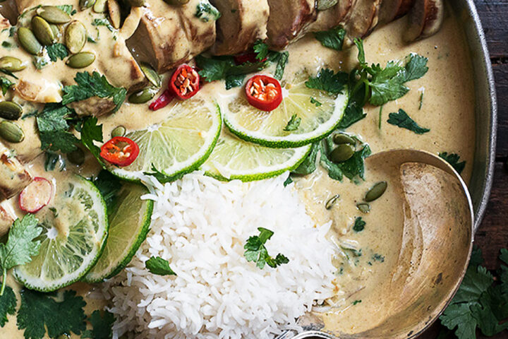 Thai green curry pork tenderloin on platter with limes and rice