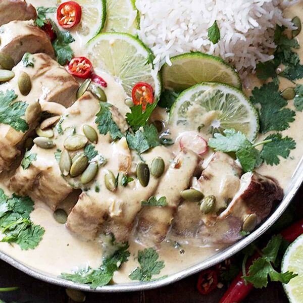 Thai green curry pork on platter with rice and limes