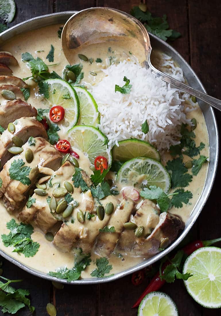 Thai green curry pork tenderloin on platter with limes and rice