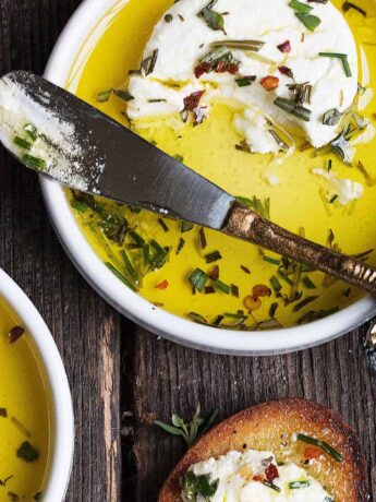 marinated goat cheese in small white bowls with knife