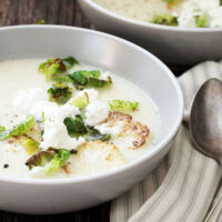 cauliflower soup in bowl with goat cheese on top