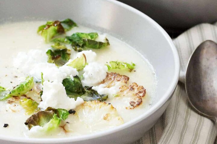 cauliflower soup in bowl with goat cheese on top
