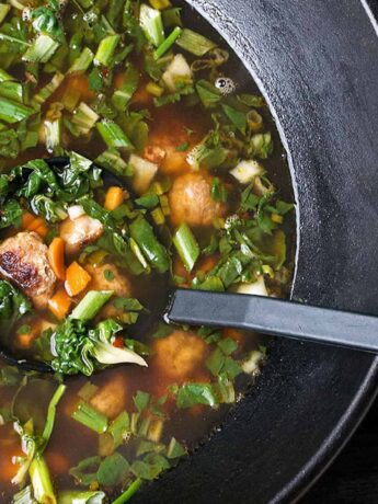 Asian-inspired pork meatball soup with bok choy in cast iron wok