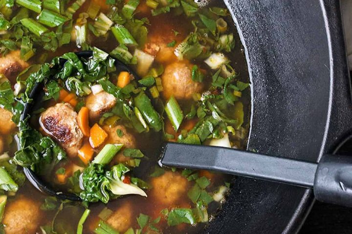 Asian-inspired pork meatball soup with bok choy in cast iron wok