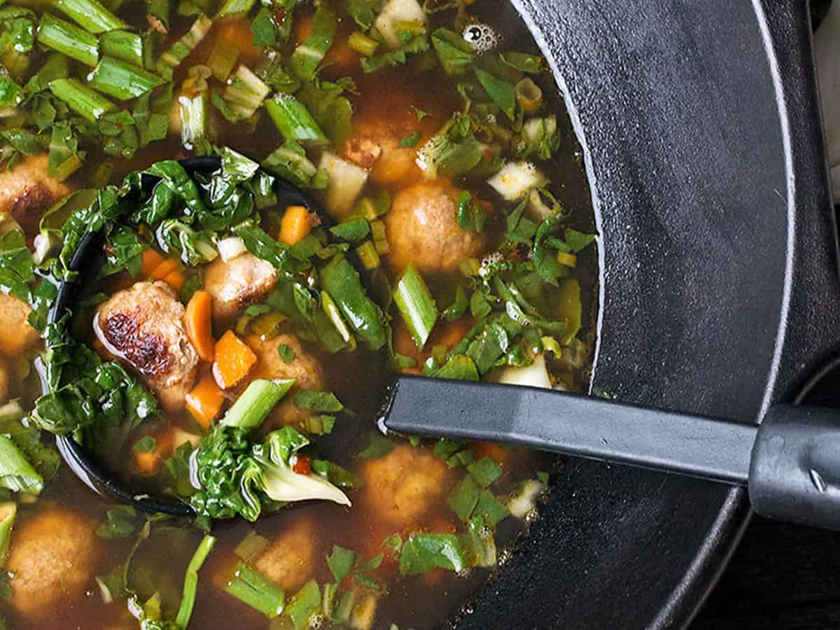 Asian-inspired pork meatball soup with bok choy in cast iron wok